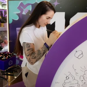 Evento empresarial realizado pela Glue para o Aiqfome: Aniversário 18 anos, bobbie goods da logo da empresa sendo pintado por