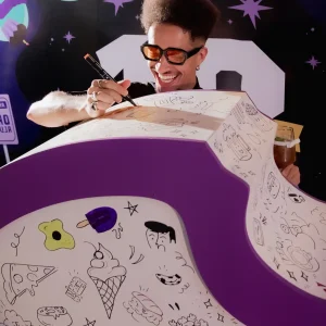 Evento empresarial realizado pela Glue para o Aiqfome: Aniversário 18 anos, bobbie goods da logo da empresa sendo pintado por